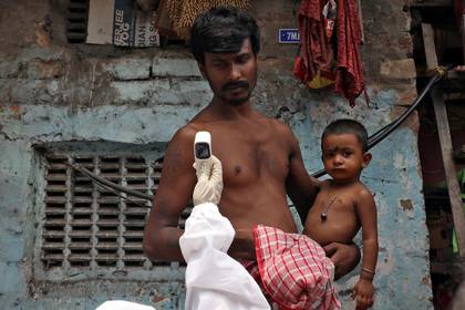 A man holds his son while a health worker takes his temperature with an infrared thermometer in a slum area of ​​Calcutta, India, on April 24, 2020. (REUTERS / Rupak De Chowdhuri)