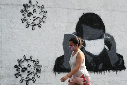 A woman passes in front of a graffiti that shows the President of Brazil, Jair Bolsonaro, adjusting his protective mask, amid the outbreak of coronavirus in Rio de Janeiro on July 2, 2020. REUTERS / Sergio Moraes